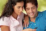 Close-up of a mid adult man and a young woman listening to an MP3 player