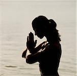 Silhouette of a mid adult woman meditating in water