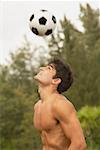 Side profile of a mid adult man playing with a soccer ball