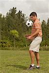 Side profile of a mid adult man playing with a soccer ball