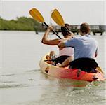 Rear view of two young men kayaking