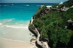 A rugged rock formation is seen next to a beach at Barbados coast Caribbean