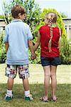 Backview of Boy and Girl Standing in Backyard Holding Hands