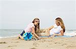 Mutter und Tochter am Strand sitzen