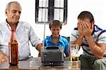 Grandfather, Father and Son Watching Television in Backyard