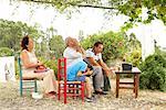 Grandfather, Grandmother, Father and Son Watching Television in Backyard