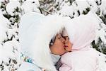 Mère embrassant bébé fille en habit de neige