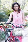 Close-up of a young woman with a bicycle in a garden