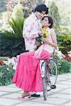 Young woman sitting on bicycle looking at a young man