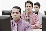 Three businessmen working on computers in an office