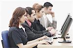 Two businessmen and two businesswomen sitting in front of computers