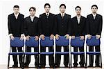 Portrait of a group of young men standing behind chairs