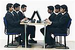 Side profile of a group of businessmen working on computers in an office