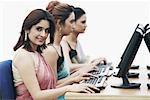 Side profile of three businesswomen working on computers in an office