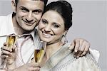 Portrait d'un jeune couple tenant des flûtes à champagne