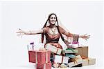 Portrait of a young woman smiling with a stack of gifts lying in front of her