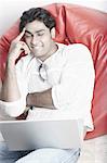 Young man sitting on a bean bag in front of a laptop