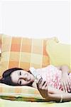 Jeune femme allongée sur un divan et tenir un téléphone mobile