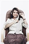 Geschäftsfrau, tragen von Kopfhörern, sitzend auf einem Bürostuhl