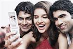 Close-up of a young woman with two young men taking a photograph of themselves