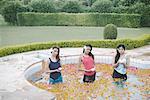 Portrait de trois jeunes femmes tenant des bougies, debout dans une piscine