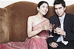 Young couple toasting with martini and whiskey glasses