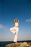 Jeune femme de faire des exercices d'yoga au bord de mer