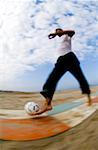 Caucasian male playing with soccer ball on beach