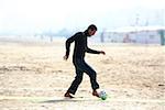 Caucasian male practicing soccer on beach