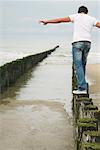 Mann, stehend auf Holzpfosten am Strand