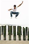 Man Jumping on Wooden Posts on Beach