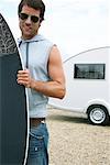 Man Holding Skimboard in Front of Trailer