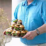 Man Carrying Plate of Small Hamburgers