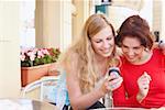 Deux jeunes femmes en regardant un téléphone mobile et souriant