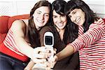 Two young women and a mid adult woman taking a photograph of themselves with a mobile phone