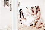 Three young women having a pillow fight on the bed