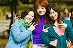 Portrait of three young women showing the peace sign