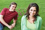 Portrait of a young woman smiling with a mid adult man lying on the grass