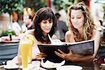 Two young women sitting at a sidewalk cafe