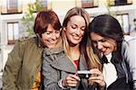 Close-up of two young women and a mid adult woman looking at a digital camera