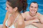 Mitte erwachsener Mann und eine junge Frau in einem Schwimmbad lächelnd