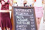 Mid section view of two women standing near a signboard