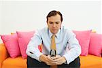 Close-up of a businessman sitting on a couch and using a mobile phone