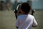 Rear view of a boy looking through coin-operated binoculars, Manhattan, New York City, New York State, USA