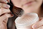 Gros plan des mains de femme, un pot de poudre pour le visage et une brosse de maquillage