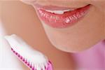 Gros plan d'une jeune femme avec une brosse à dents devant sa bouche