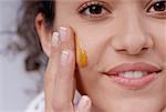 Portrait of a young woman applying honey on her cheek