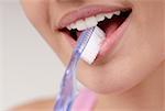 Gros plan d'une jeune femme avec une brosse à dents dans sa bouche