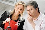 Close-up of a mid adult woman cooking food with a mature man eating food in the kitchen