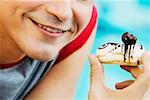Close-up of a young man holding an eclair and smiling